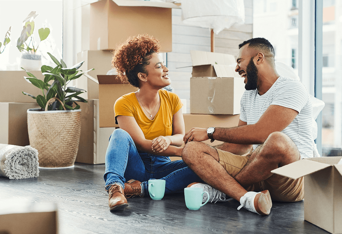 A couple sits among boxes in their new home, getting ready to unpack and settle in.