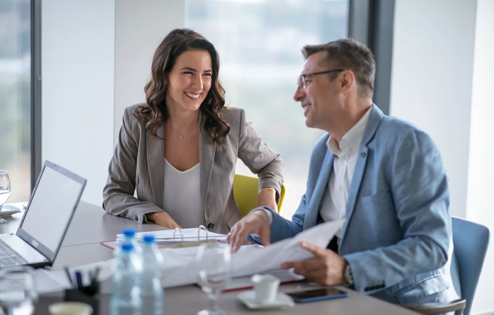 Two people sitting at a conference table chatting.